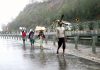 Labourers walk along highway during rains in Jammu on Friday. (UNI)