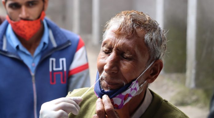 A Health worker collects nasal swab sample of a man for COVID-19 test in Poonch on Thursday. (UNI)