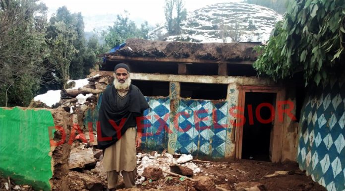An elderly man standing on the wreckage after his house collapsed due to landslide in Mahore area of Reasi on Monday. — Excelsior/Romesh Mengi