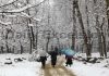 People walk through a snow-covered orchard during heavy snowfall in Tangmarg area of Baramulla district. -Excelsior/Aabid Nabi