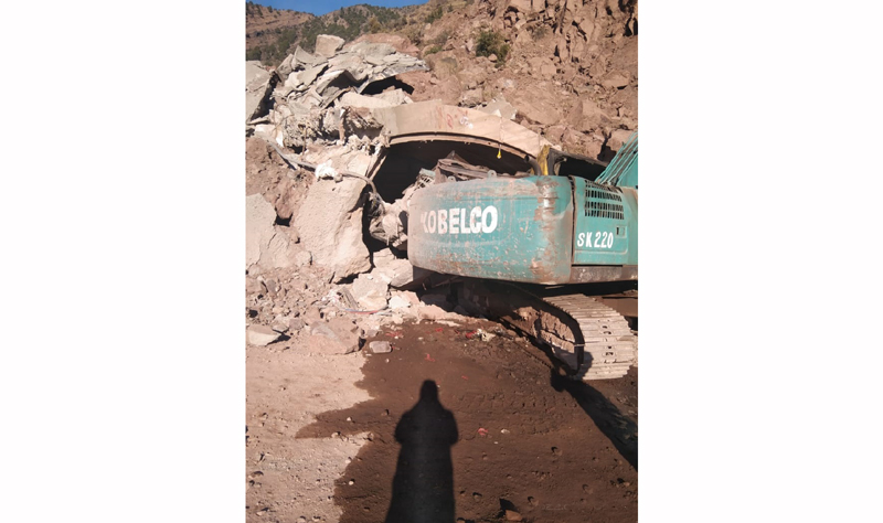 A machine partially burried under landslide at Railway Tunnel site in Sawalkote.