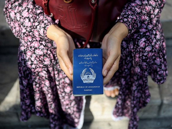 An Afghan refugee holds her passport in front of the German Embassy in a bid to acquire refugee visas from the European country, in Tehran
