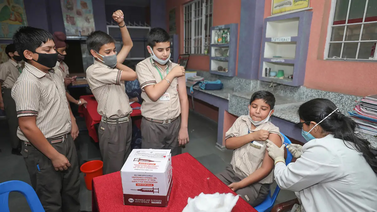 A healthcare worker administers a dose of COVID-19 preventive vaccine to a student in the age group of 12-14 years, at a school in Jammu,