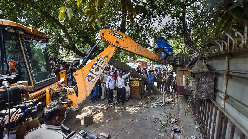 A bulldozer razes an illegal structure during an anti-encroachment drive by the MCD at the New Friends Colony, in New Delhi.
