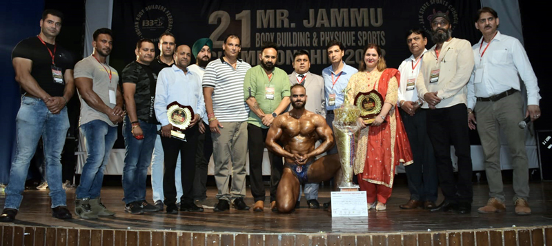 A winner displaying muslces while posing for photograph with dignitaries at Teacher Bhawan, Gandhi Nagar in Jammu on Sunday. A winner displaying muslces while posing for photograph with dignitaries at Teacher Bhawan, Gandhi Nagar in Jammu on Sunday.