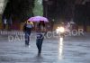 A woman taking umbrella cover walks along a Jammu road amidst heavy rain on Thursday morning. -Excelsior/Rakesh