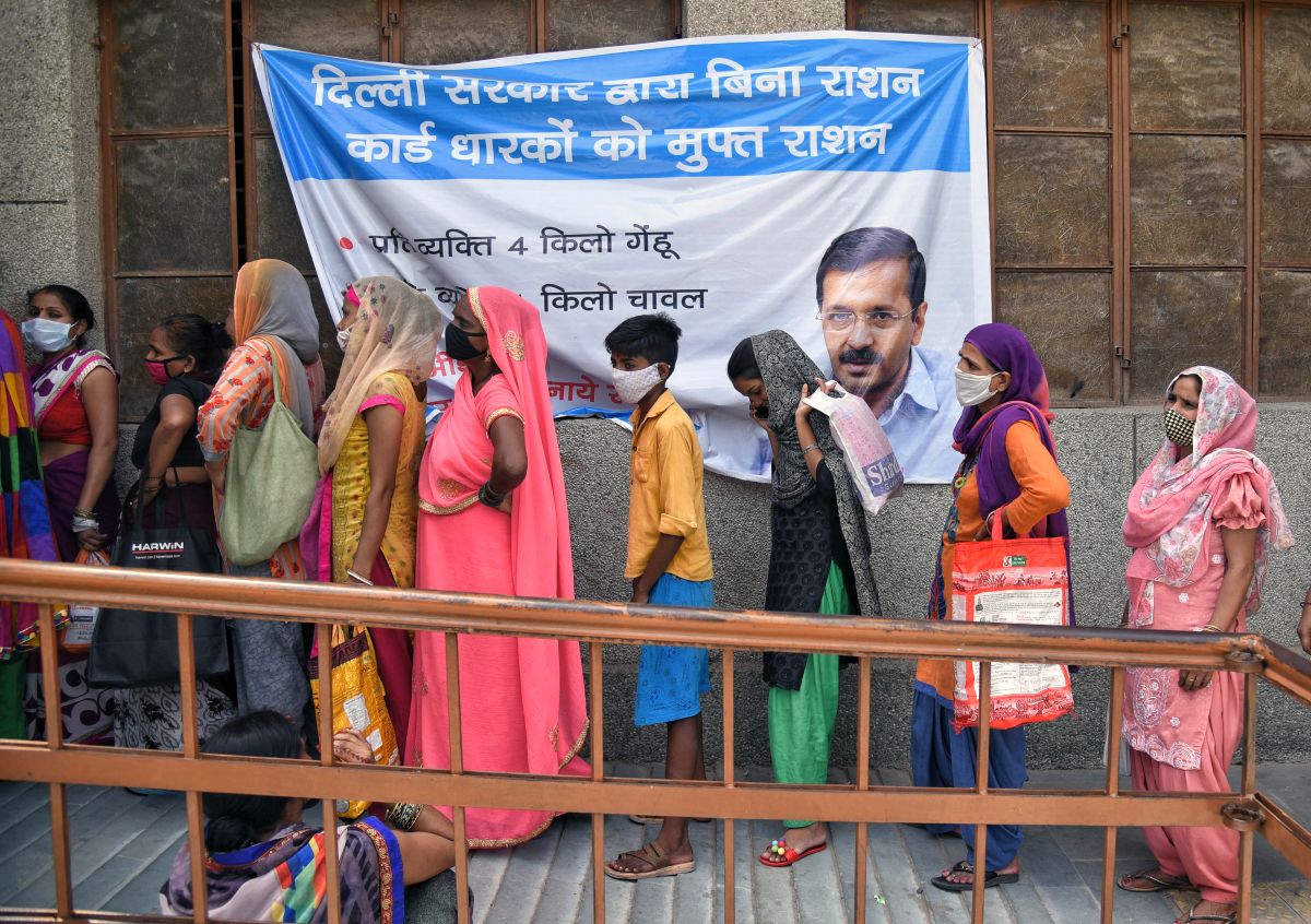 Women stand in a queue outside a government school for getting dry ration by Delhi government