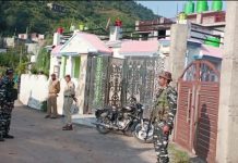 Security personnel stand guard outside a house during SIA raids in Poonch on Wednesday.