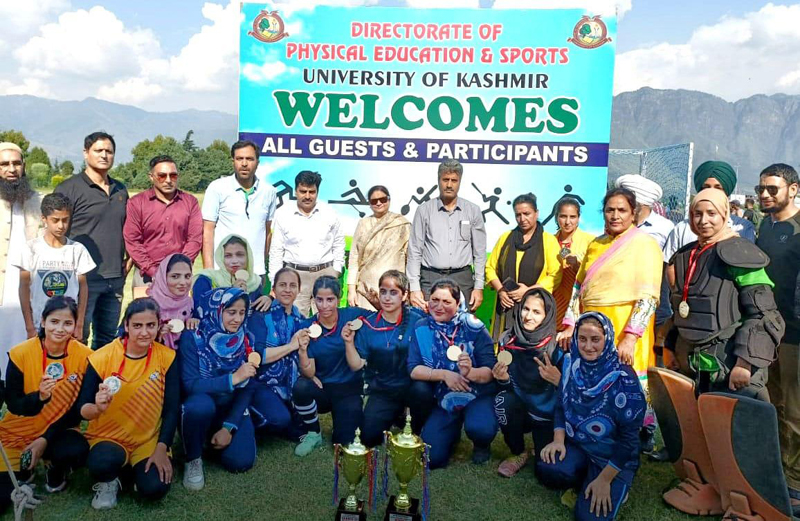 Winners displaying trophies and medals while posing for a group photograph at University of Kashmir on Friday.