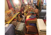 A vendor displaying saree before customers at Hastahshilpi Silk India Expo in Jammu on Monday. - Excelsior/Rakesh