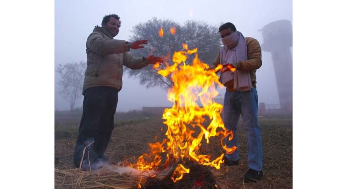 People warm themselves next to a bonfire on a cold morning on the outskirts of Jammu. -Excelsior/Rakesh