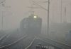 A train runs through dense fog during a winter morning