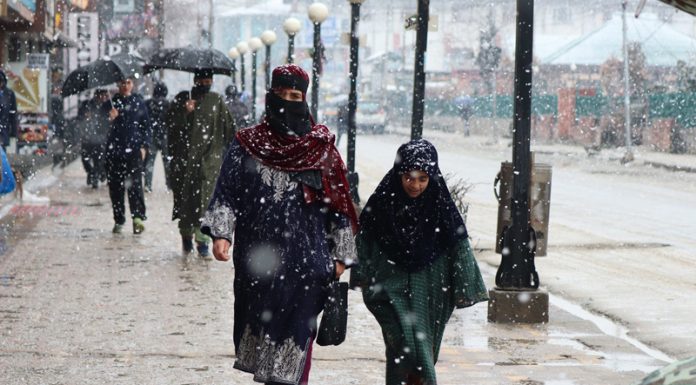People walk during fresh snowfall in Srinagar. -Excelsior/Shakeel