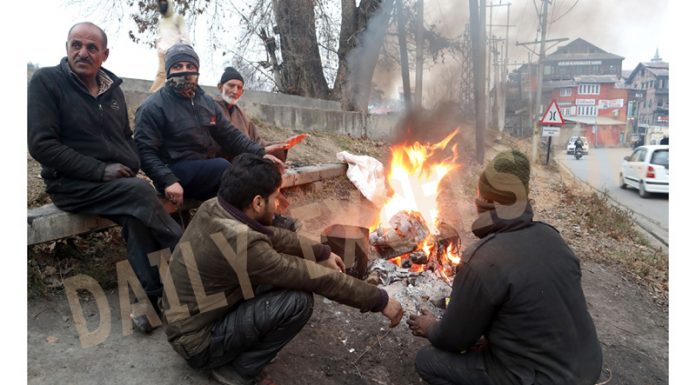 Group of locals warming themselves on a roadside in Srinagar on Sunday.. - Excelsior/Shakeel