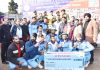 Winner displaying trophy and cash prize while posing with dignitaries at Poonch.