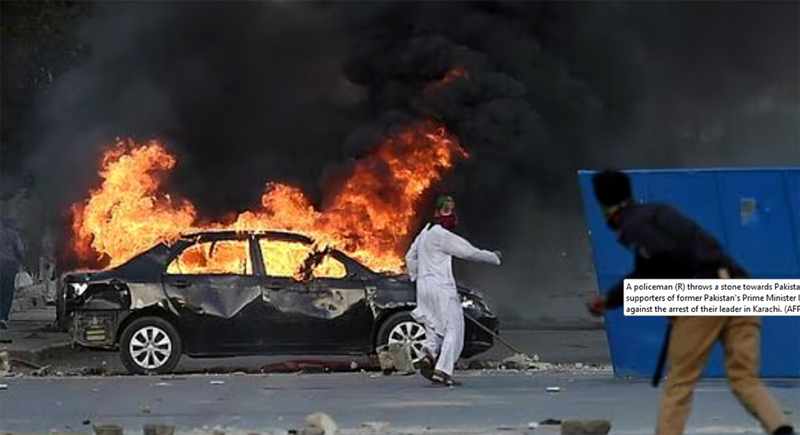 A policeman (R) throws a stone towards Pakistan Tehreek-e-Insaf party activists blocking a road during a protest against the arrest of Imran Khan in Karachi on Wednesday. A policeman (R) throws a stone towards Pakistan Tehreek-e-Insaf party activists blocking a road during a protest against the arrest of Imran Khan in Karachi on Wednesday.