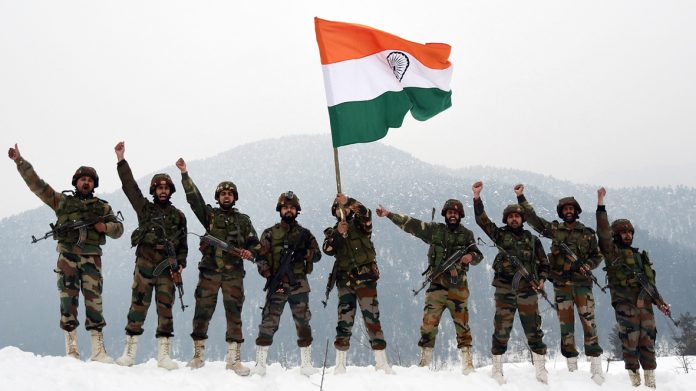 Army Jawans hold the National Flag and raise slogans near the snow-covered border