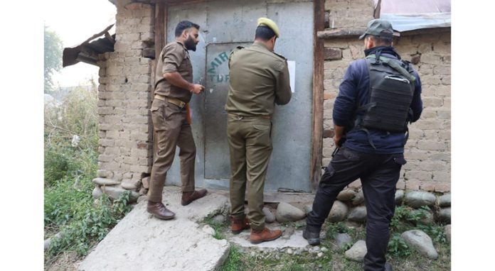 Cops attaching a house in Kulgam on Wednesday.