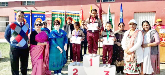 Students posing on podium with medals and certificates.