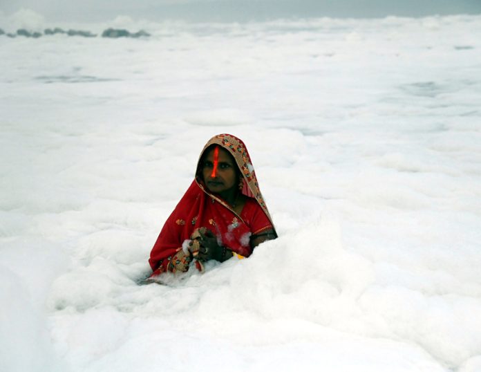 Chhath devotee offering arghya to rising Sun standing in toxic foam floated in polluted Yamuna river on the last day of Chhath festival, in New Delhi on Monday. (UNI) Chhath devotee offering arghya to rising Sun standing in toxic foam floated in polluted Yamuna river on the last day of Chhath festival, in New Delhi on Monday. (UNI)