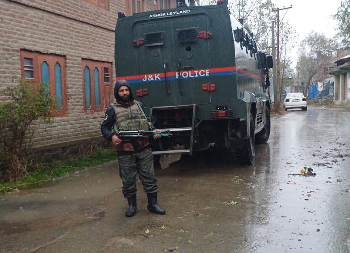 A security personnel stands guard during SIA raid at Jablipora, Bijbehara in Anantnag district on Friday. —Excelsior/Sajad Dar