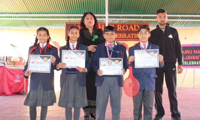 Students of Army Public School Dhar Road Udhampur displaying certificates while posing with the Principal and Coach.