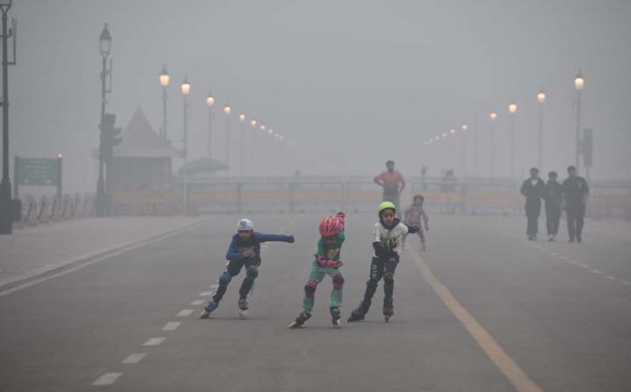 Children skates on Kartvya Path near India Gate amid dense fog enflugs, in New Delhi on Sunday. (UNI)