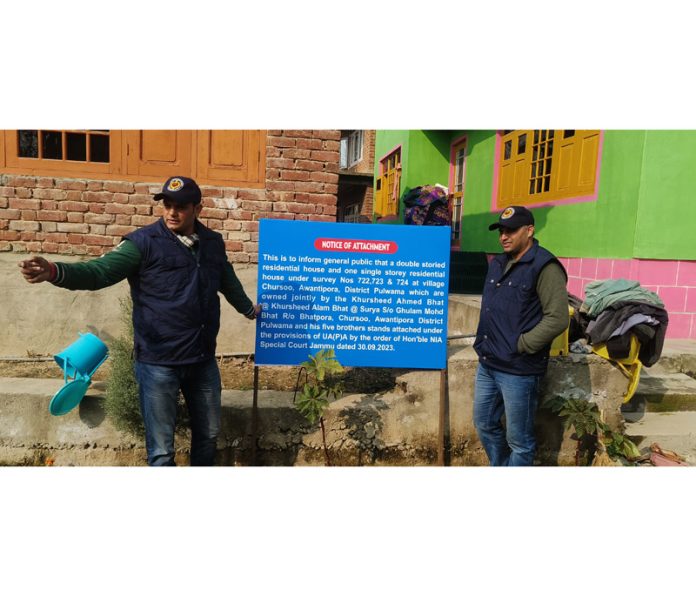 NIA team installing board of property attachment at Chursoo, Awantipora. —Excelsior/Younis Khaliq
