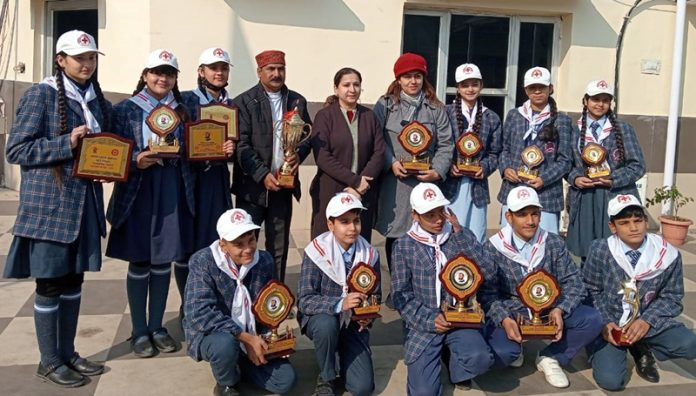 Students of DBN Amarvilla displaying trophies while posing with dignitaries.