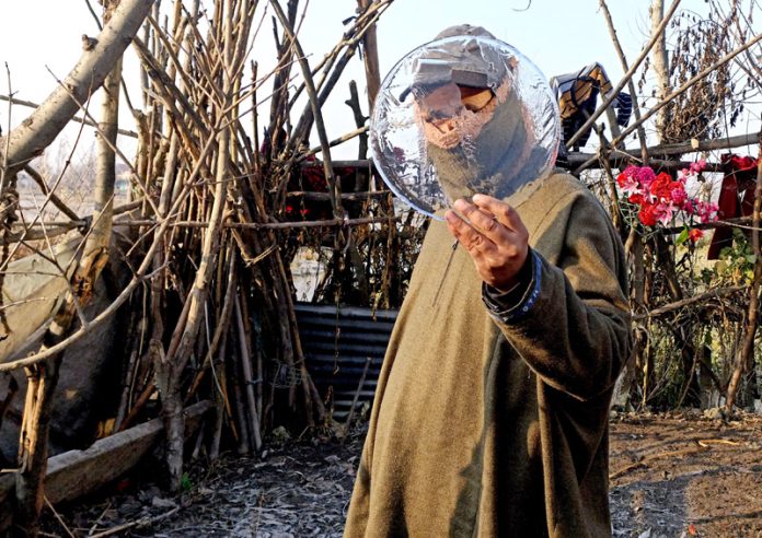 A man poses with a piece of frozen ice in the interiors of Dal lake on Thursday. -Excelsior/Shakeel
