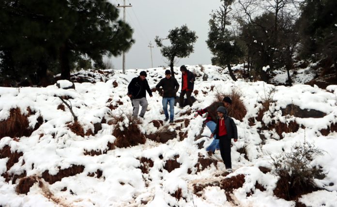 People enjoying season’s first snowfall near LoC in Bhimber Gali area of Poonch on Thursday. -Excelsior/Rahi Kapoor