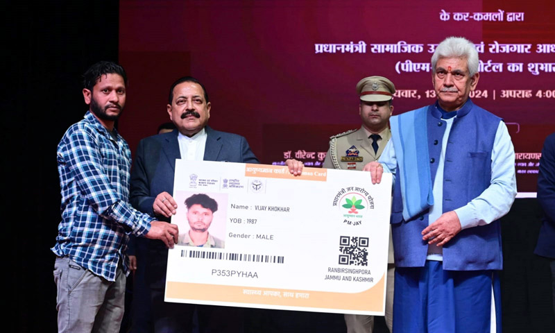 LG Manoj Sinha and Union Minister Dr Jitendra Singh giving Ayushman Health Card to a beneficiary