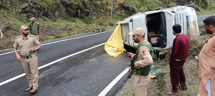 Cops standing near the passenger vehicle that overturned on road in Doda on Thursday. — Excelsior/Tilak Raj