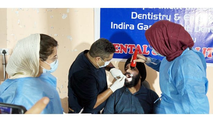 A doctor from IGGDC&H examining a patient during a dental camp in Jammu.