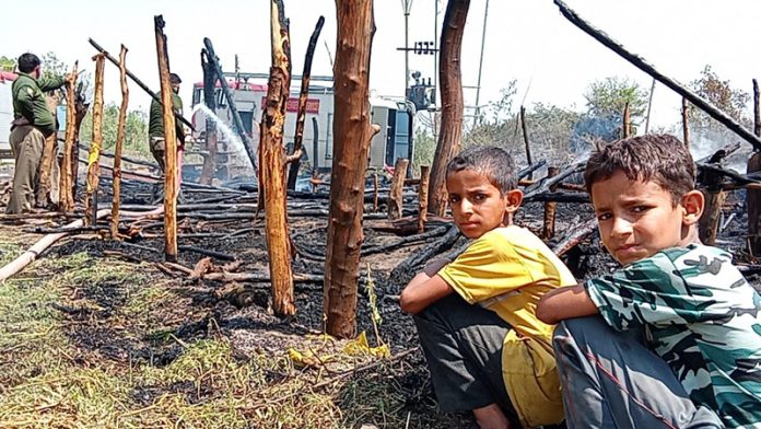 Two nomadic children sit by the side of their hutment that got completely damaged in a devastating fire in Arnia on Wednesday. Two nomadic children sit by the side of their hutment that got completely damaged in a devastating fire in Arnia on Wednesday.