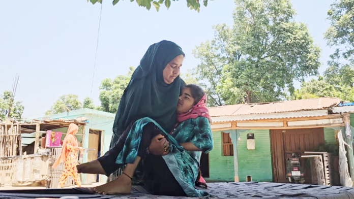 A mother carries her child, suffering from a mysterious disease, in her lap in Panassa village of Reasi district.
