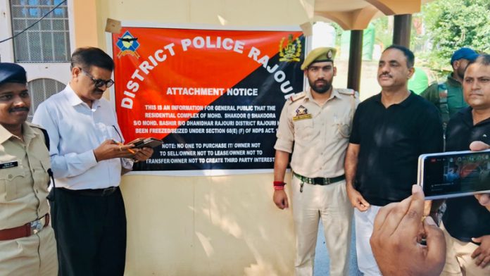 Officials paste attachment notice on seized property of drug peddler in Rajouri.