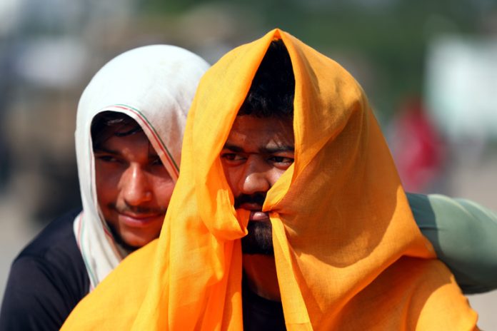 Protecting themselves from blazing Sun, two persons cover their heads while walking on a Jammu road on Wednesday. -Excelsior/Rakesh