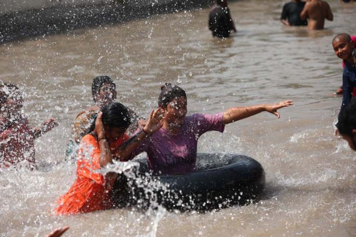 People beating the heat by bathing in cold water of Ranbir Canal’s distributory in Jammu on Monday. -Excelsior/Rakesh