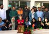 University of Kashmir players displaying trophy and medals while posing with dignitaries.