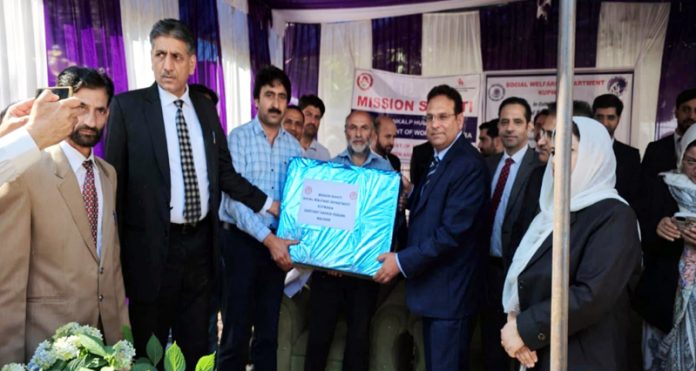 Justice Wasim Sadiq Nargal distributing wheelchairs, old-age sticks and cheques among the beneficiaries at Kupwara.
