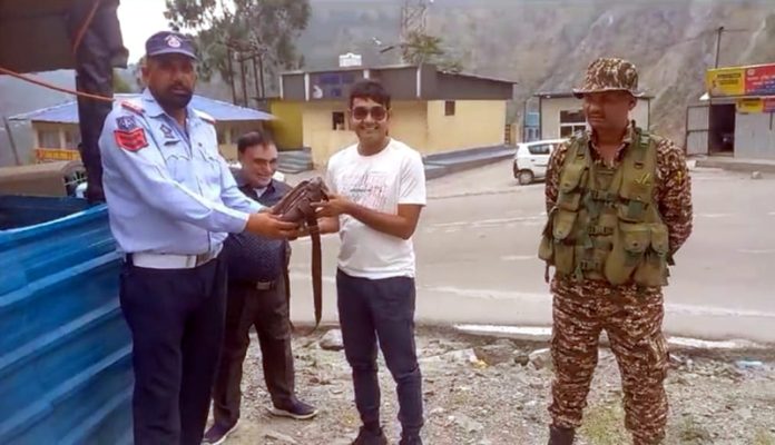 Traffic cops return the bag full of cash and valuables to its owner in Ramban on Monday. Traffic cops return the bag full of cash and valuables to its owner in Ramban on Monday.