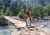Reshwari Handwara resident crossing the unsafe wooden bridge over Mawar stream on Tuesday. -Excelsior/Aabid Nabi