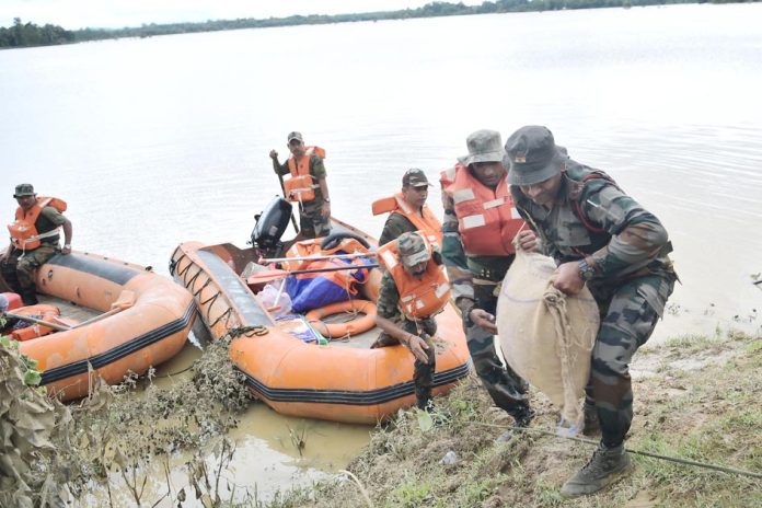 AGARTALA, AUG 26 :- Assam Rifles personnel carrying relief materials to distribute to marooned people in Amarpur city, some 82km away from Agartala on Monday.UNI 