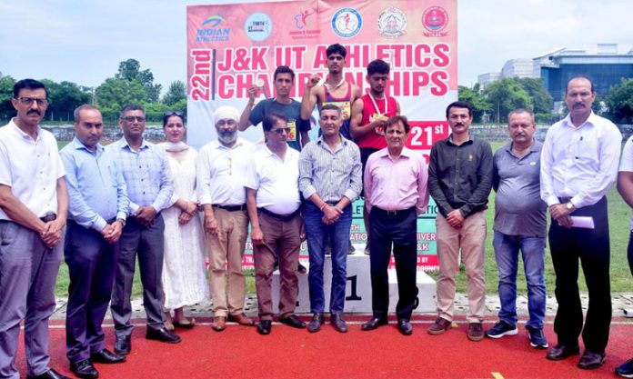 Athletes posing with medals on podium along with dignitaries during Athletics Championship.