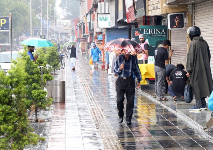 Commuters during heavy rain in Srinagar on Thursday.