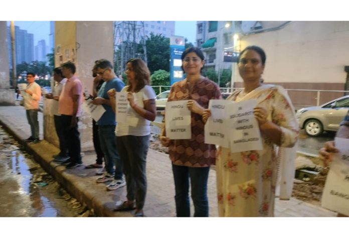 People displaying posters with slogans in solidarity with Bangladeshi Hindus during candle light march at Gurugram.