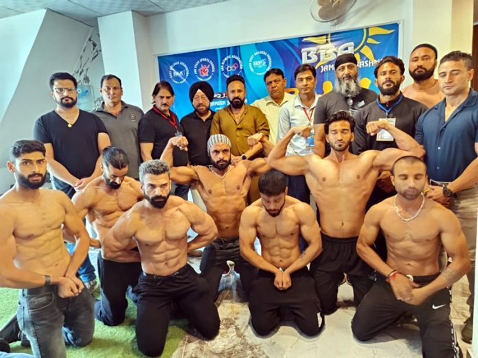 Bodybuilders displaying their muscles during weighing session.