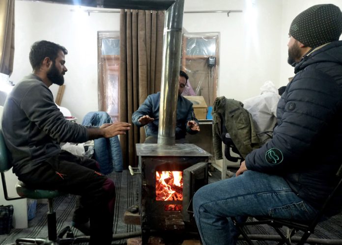 Employees warming up themselves in a office on Wednesday morning after Srinagar records season's first subzero temperature. -Excelsior/Shakeel