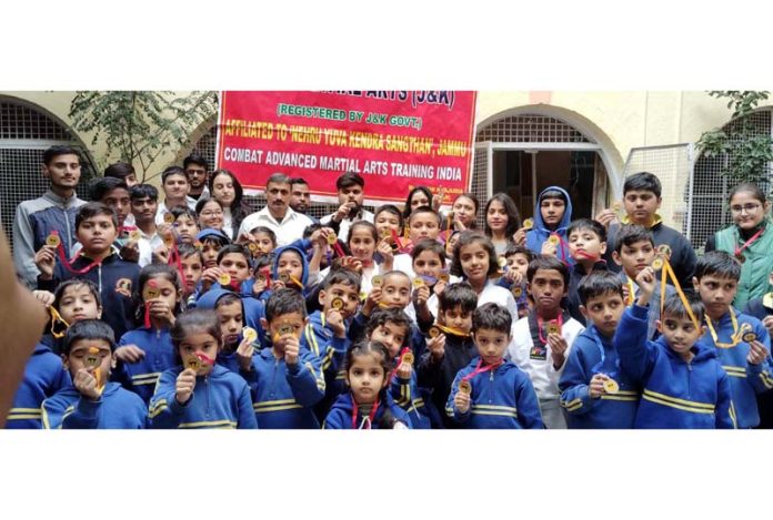 Martial arts students posing along with medals during a championship.